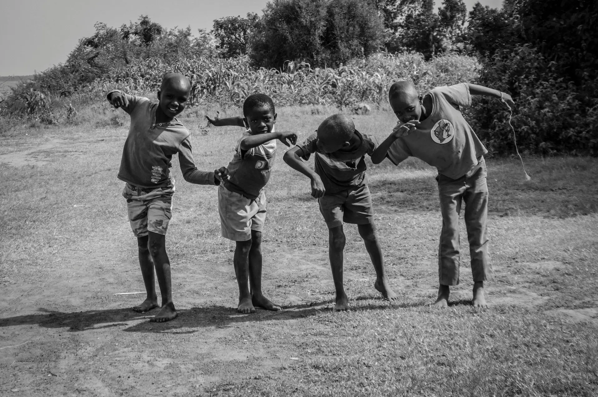 Black and white photo capturing joyful African children playing outdoors in Kisumu, Kenya.